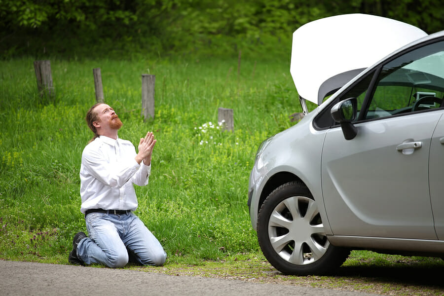 Funny driver praying a broken car by the road